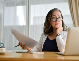 Woman sits at desk and looks at laptop