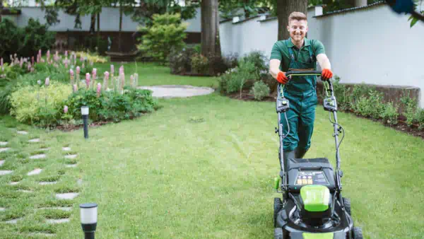 Man in overalls mowing lawn