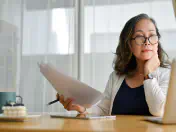 Woman sits at desk and looks at laptop