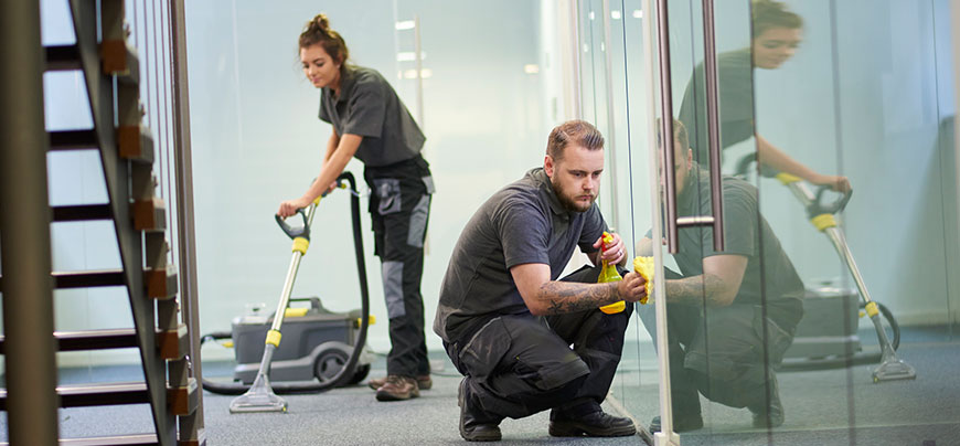 Two workers clean an office